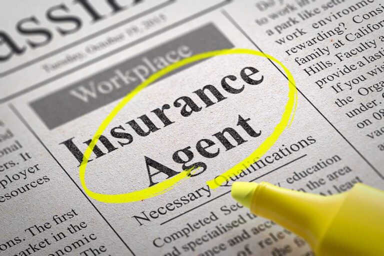A couple reviews life insurance documents at a kitchen table beside a calculator and household budget.